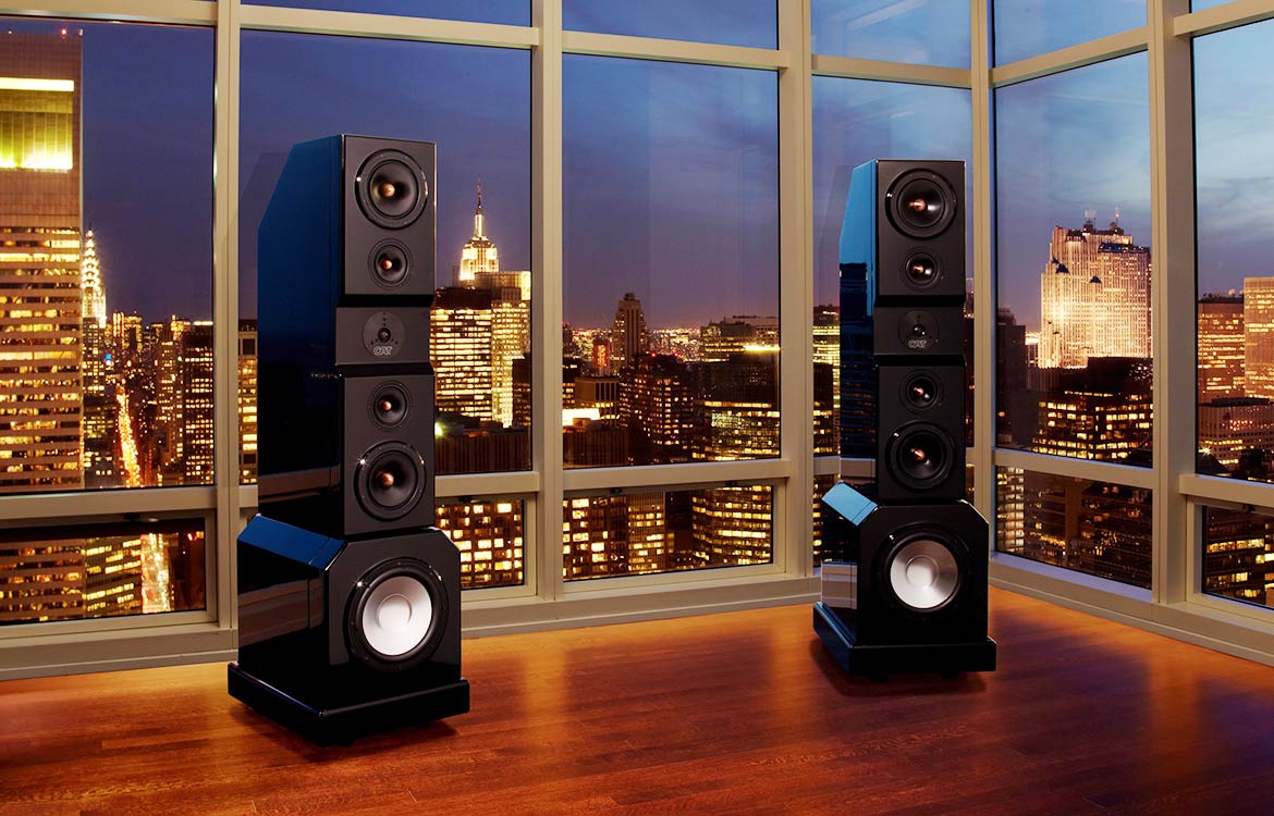 CAT Floor standing speakers in a NYC loft in front of picture windows overlooking a cityscape at dusk
